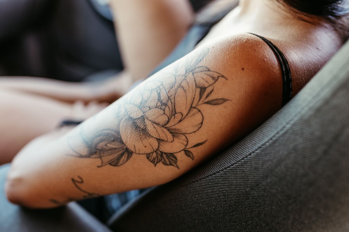 Tatuagem floral feminina delicada no braço de uma mulher